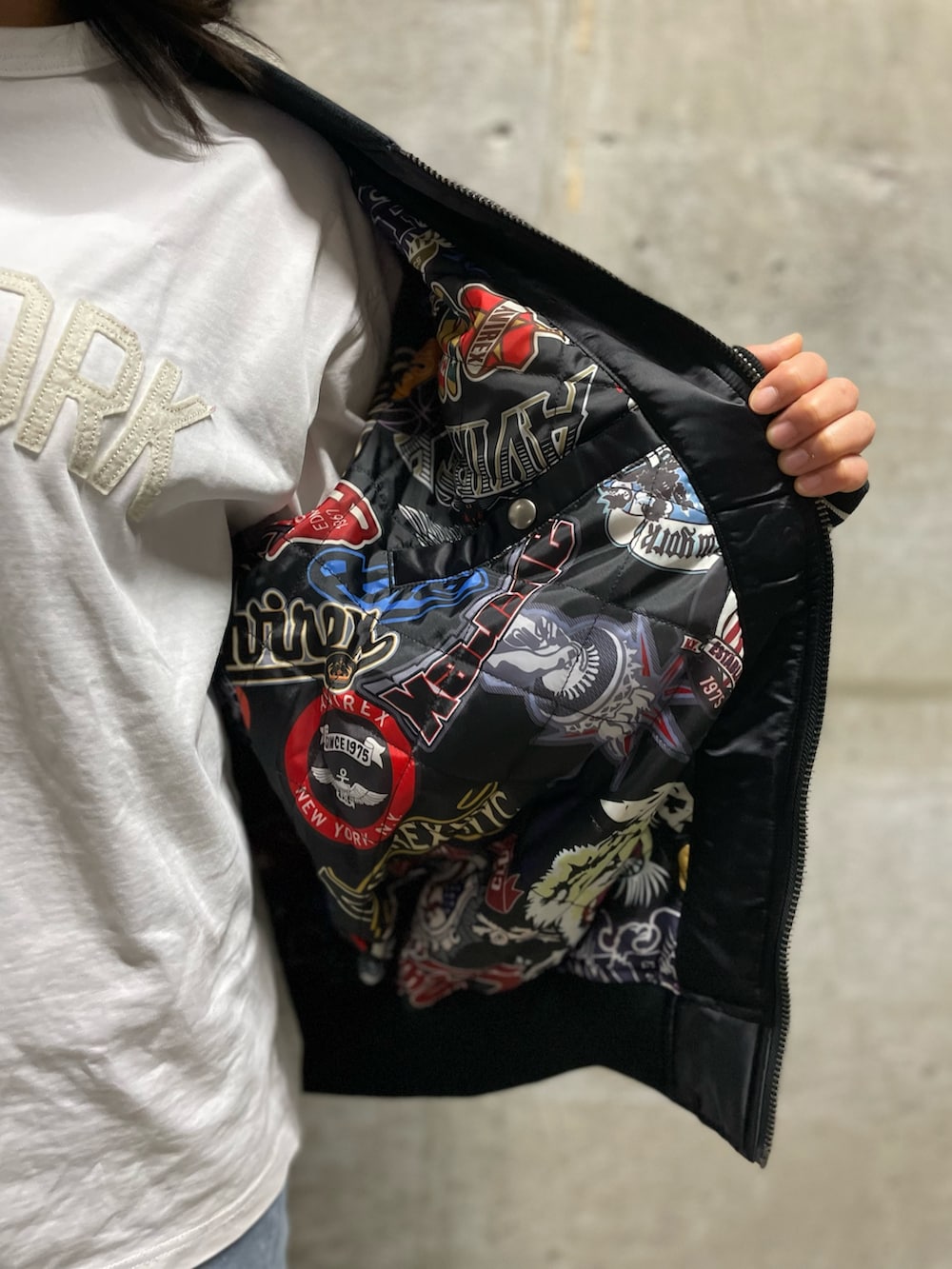 ホワイト系のTシャツ/カットソー、ブラック系のスタジャン、ブルー系のデニムパンツを着用したレディースの秋コーディネートの5枚目の写真