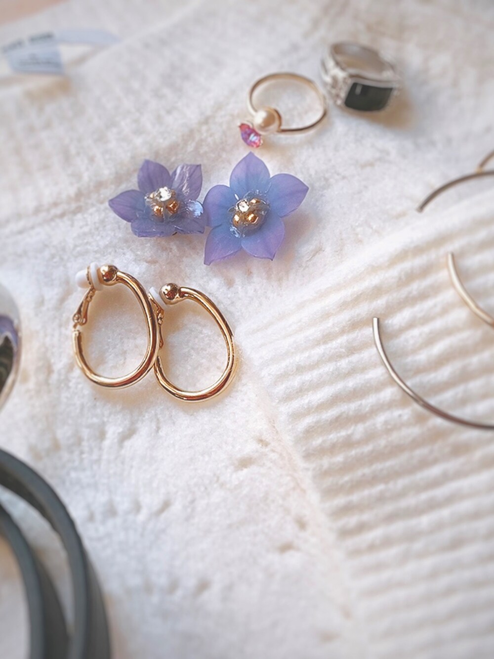 ホワイト系のニット/セーター、シルバー系のブレスレット、パープル系のピアス（両耳用）を着用したレディースの秋コーディネートの2枚目の写真