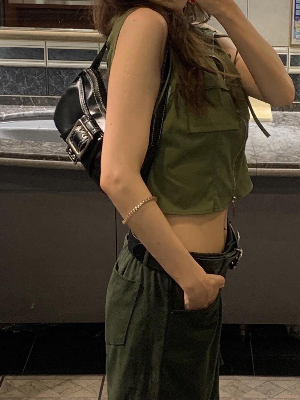 グリーン系のトップス、グリーン系のパンツ、ブラック系のバッグを着用したレディースの夏コーディネートの2枚目の写真