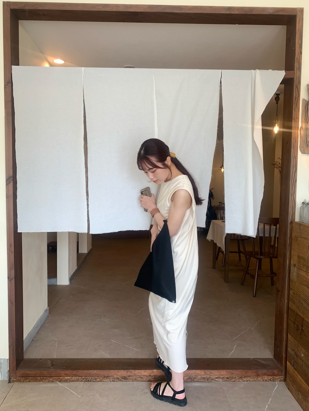 ブラック系のショルダーバッグ、ホワイト系のワンピースを着用したレディースの夏コーディネートの3枚目の写真