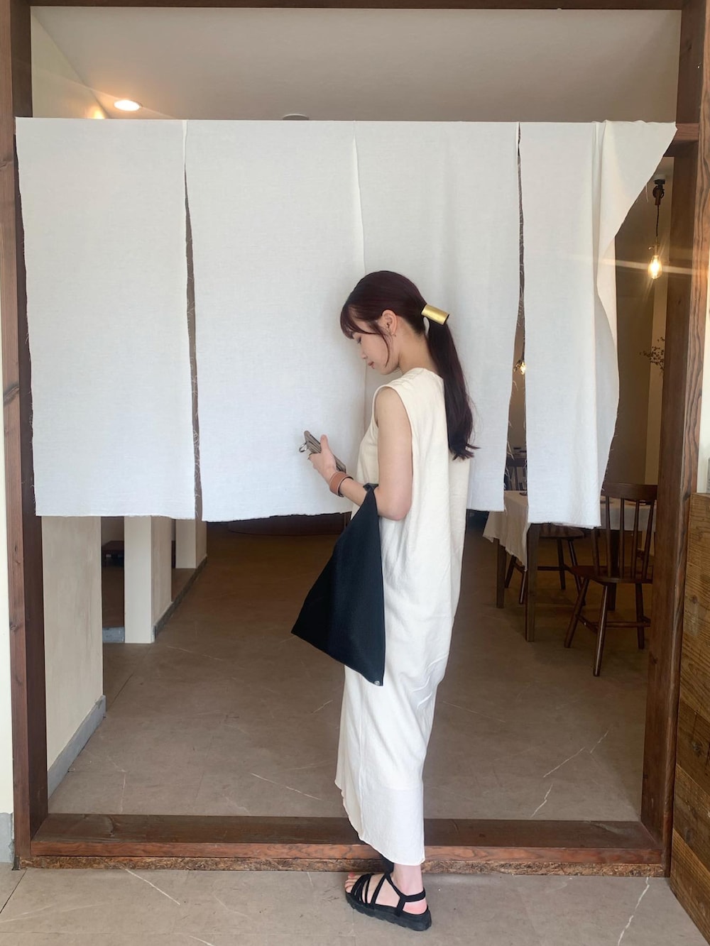 ブラック系のショルダーバッグ、ホワイト系のワンピースを着用したレディースの夏コーディネートの2枚目の写真