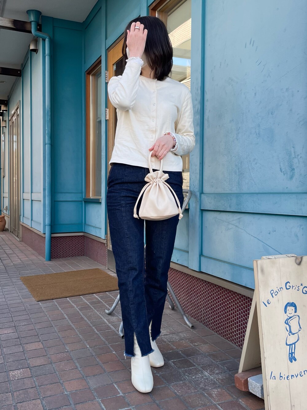 ブルー系のデニムパンツ、ホワイト系のブーツ、ホワイト系のショルダーバッグを着用したレディースの冬コーディネートの2枚目の写真