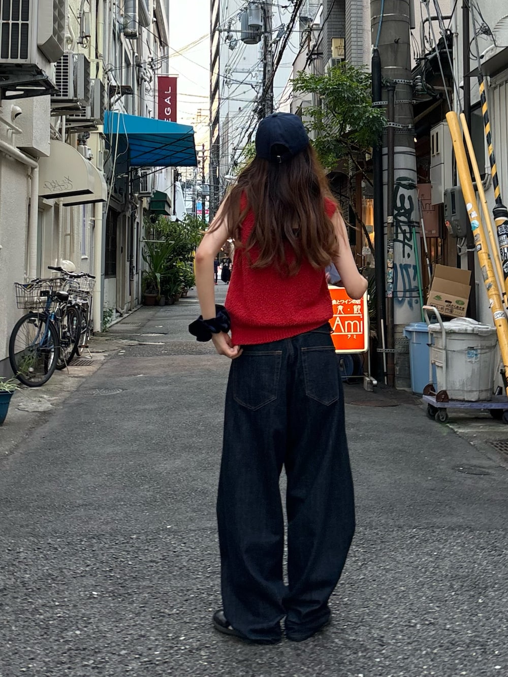 レッド系のタンクトップ、ブルー系のデニムパンツ、ブルー系のキャップを着用したレディースの夏コーディネートの2枚目の写真