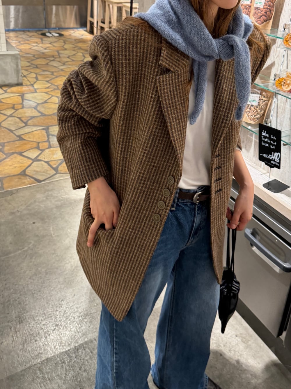 ブルー系のデニムパンツ、イエロー系のテーラードジャケット、ブラック系のショルダーバッグを着用したレディースの秋コーディネートの2枚目の写真