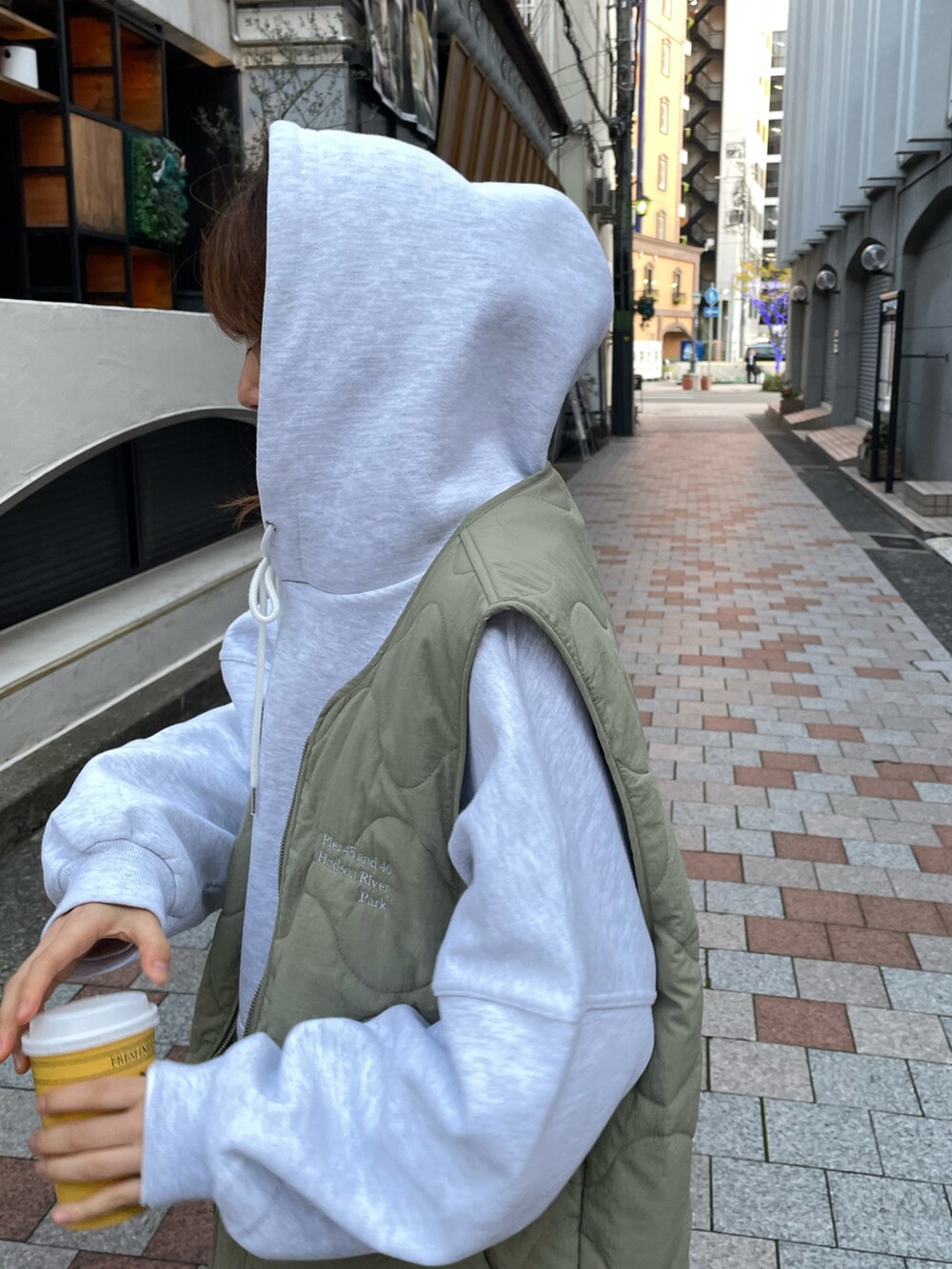 グレー系のパーカー、グリーン系のベスト、ブラック系のレギンス/スパッツを着用したレディースの秋コーディネートの2枚目の写真