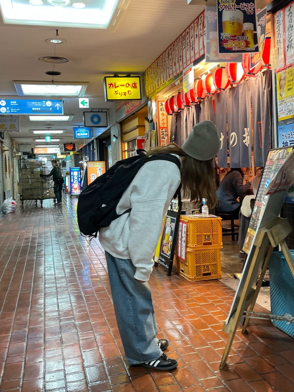 グレー系のスウェット、ブルー系のデニムパンツ、ブラック系のバックパック/リュックを着用したレディースの冬コーディネートの2枚目の写真