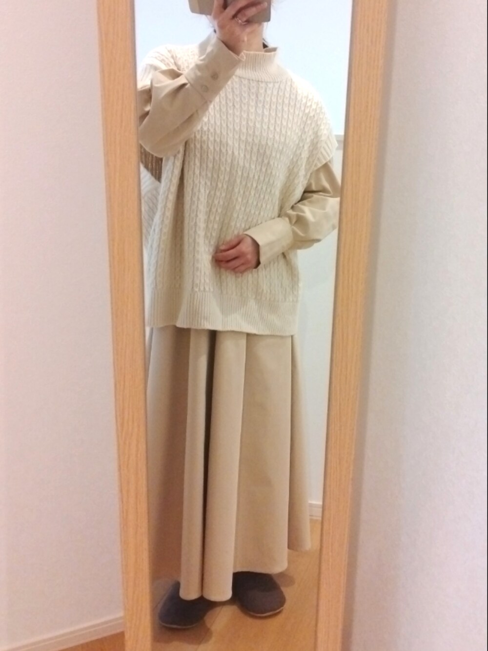 ホワイト系のベスト、ベージュ系のワンピース、ホワイト系のマフラーを着用したレディースの冬コーディネートの2枚目の写真