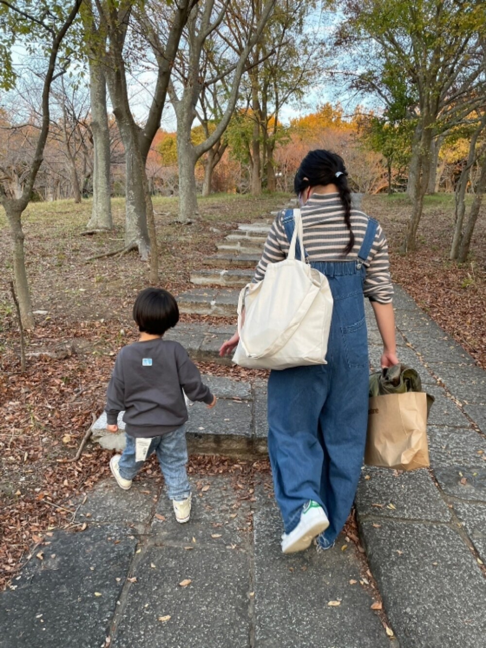 グレー系のニット/セーター、ブルー系のサロペット/オーバーオール、グリーン系のモッズコートを着用したレディースの秋コーディネートの2枚目の写真