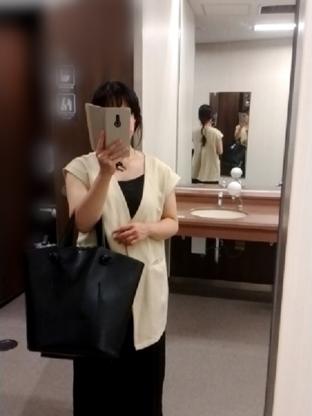 ブラック系のトートバッグ、ホワイト系のベスト、ブラック系のスリッポンを着用したレディースの夏コーディネートの2枚目の写真