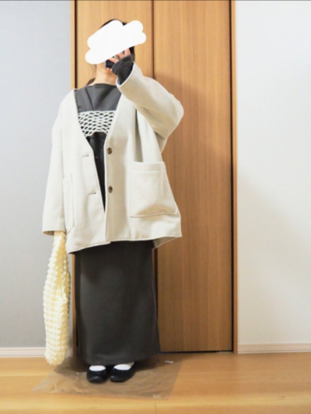 ホワイト系のトートバッグ、グレー系のワンピース、ホワイト系のベストを着用したレディースの冬コーディネートの2枚目の写真