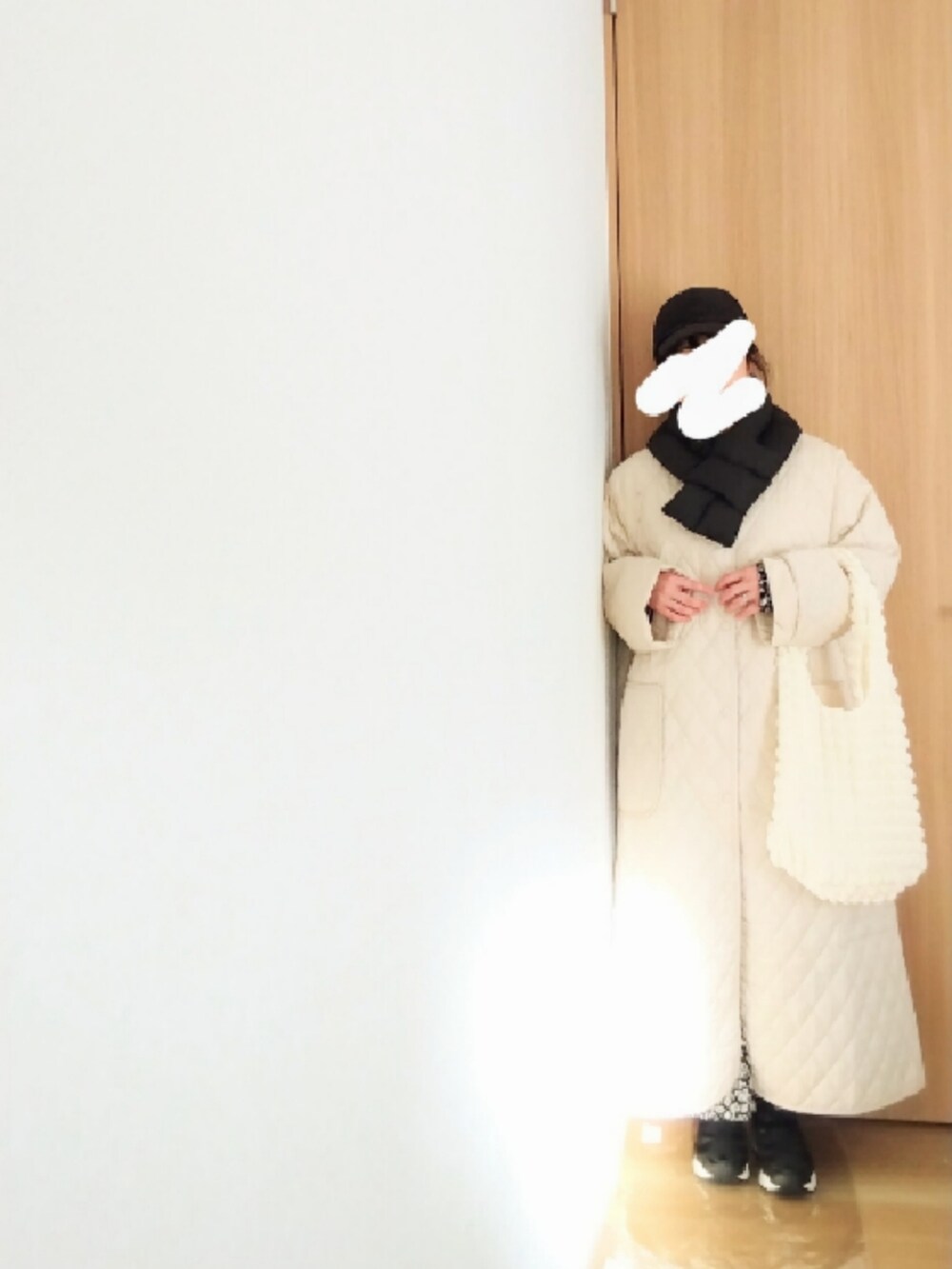 ホワイト系のノーカラーコート、ホワイト系のベスト、ブラック系のワンピースを着用したレディースの冬コーディネートの2枚目の写真