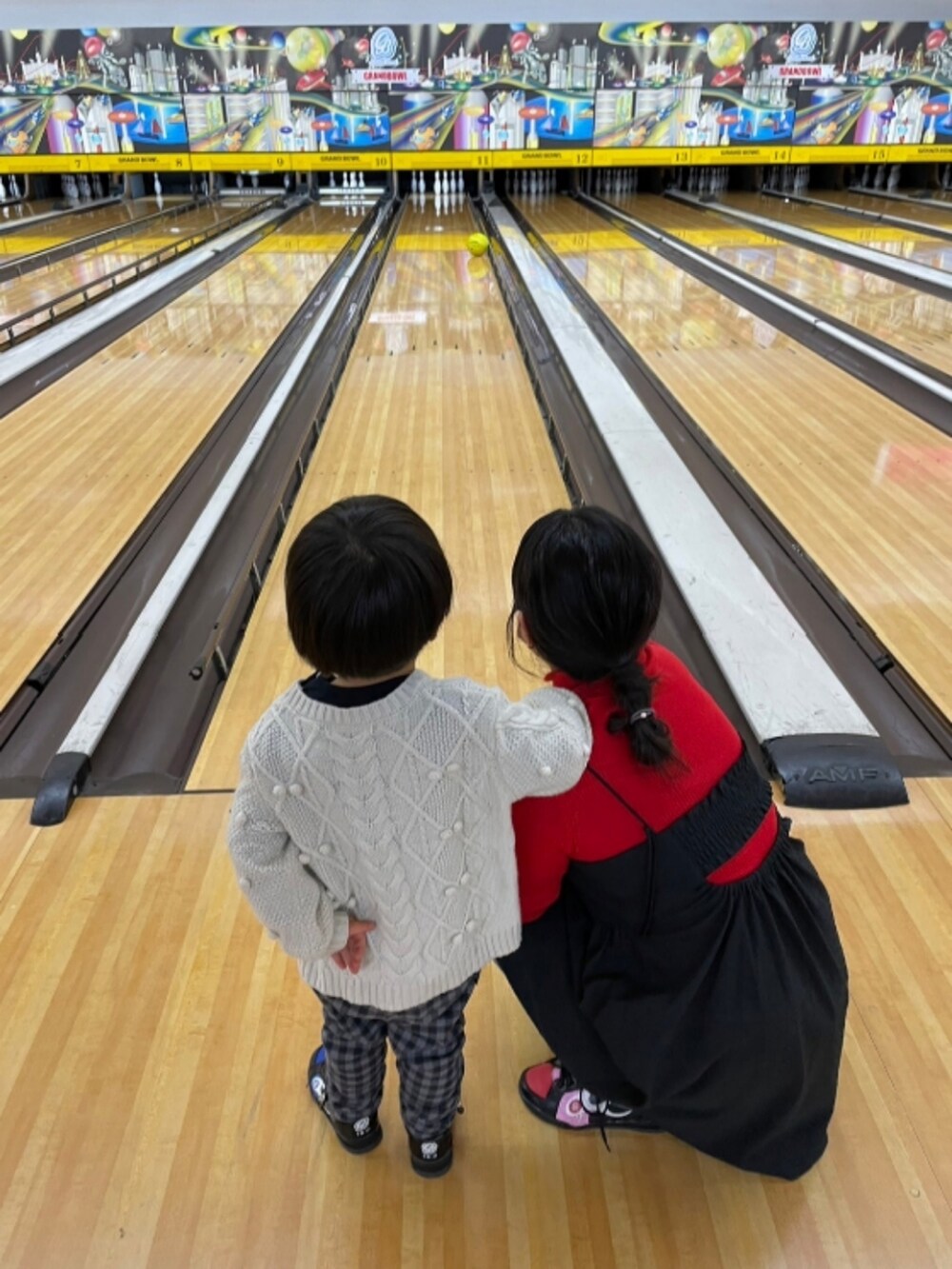 ブラック系のダウンジャケット/コート、レッド系のニット/セーター、ブラック系のワンピースを着用したレディースの冬コーディネートの2枚目の写真