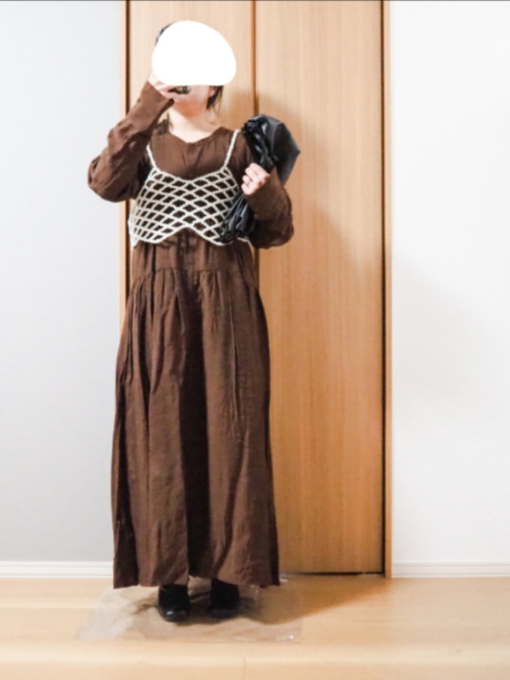 ホワイト系のベスト、ブラウン系のワンピースを着用したレディースの冬コーディネートの2枚目の写真