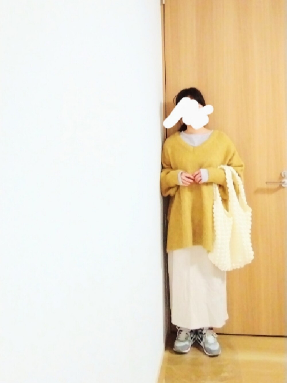 ホワイト系のノーカラーコート、イエロー系のニット/セーター、グレー系のTシャツ/カットソーを着用したレディースの冬コーディネートの2枚目の写真