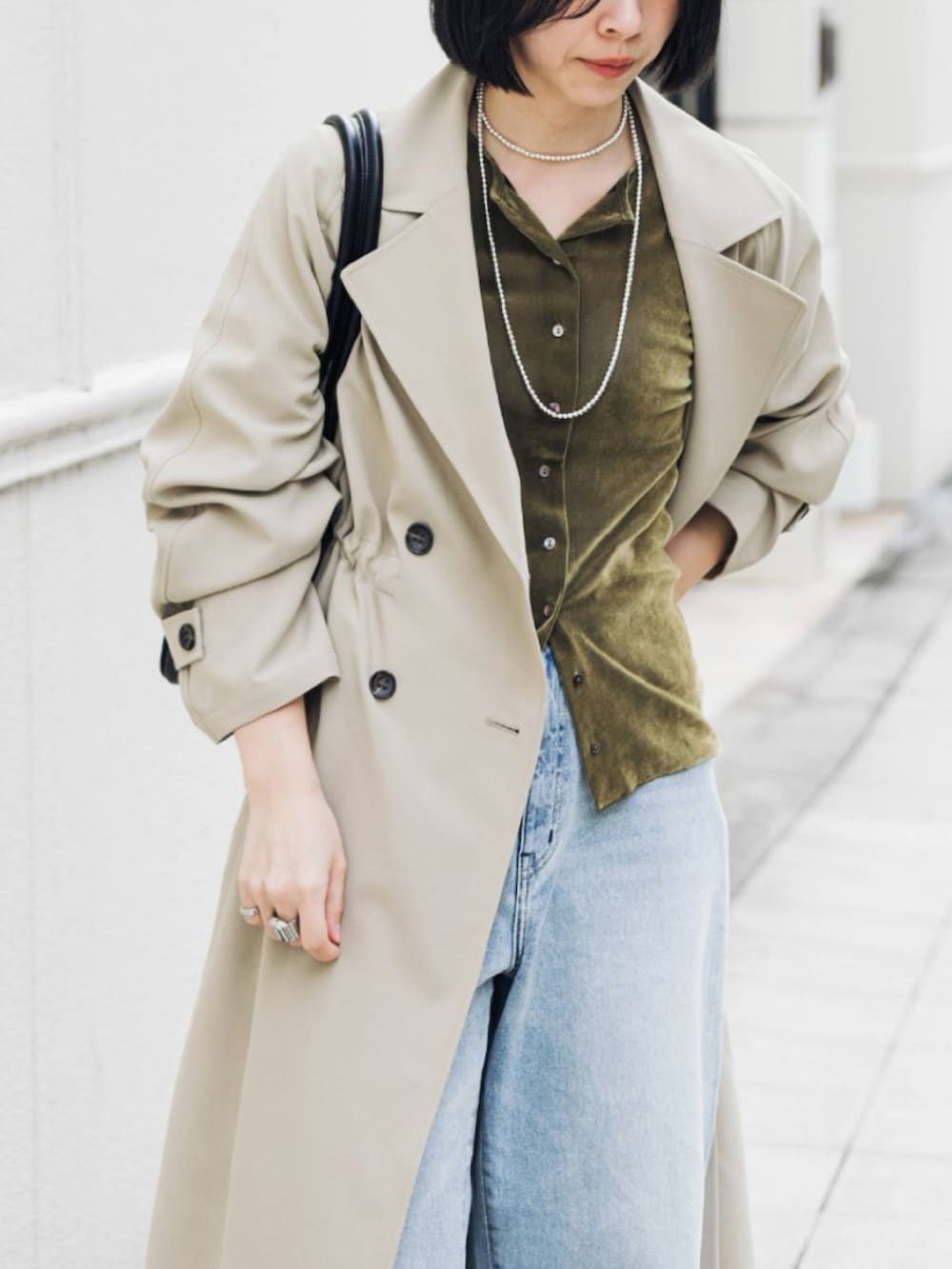 ベージュ系のトレンチコート、グリーン系のカーディガン/ボレロ、ブルー系のデニムパンツを着用したレディースの冬コーディネートの5枚目の写真