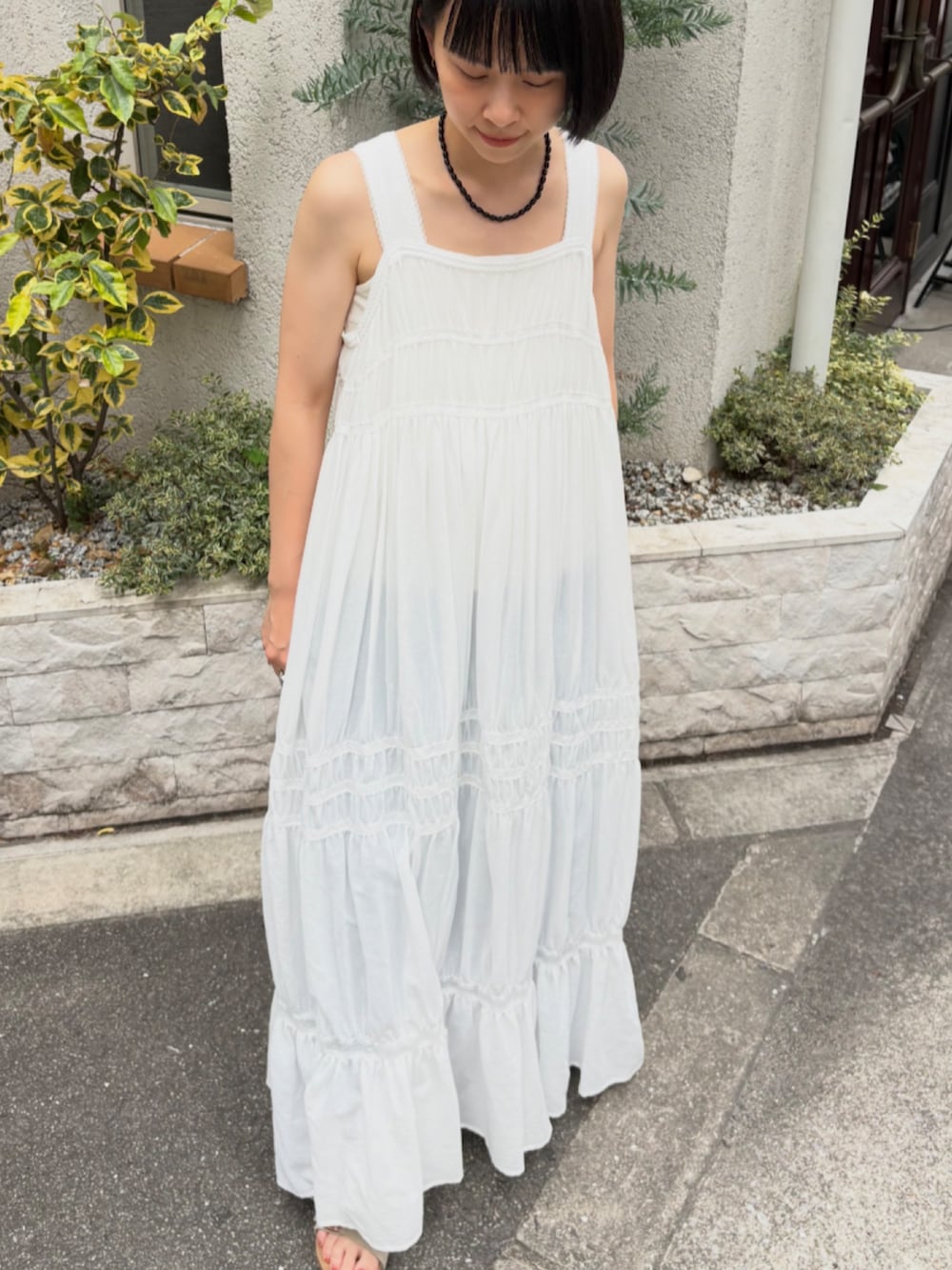 ホワイト系のワンピース、ブルー系のデニムパンツ、ベージュ系のサンダルを着用したレディースの夏コーディネートの3枚目の写真
