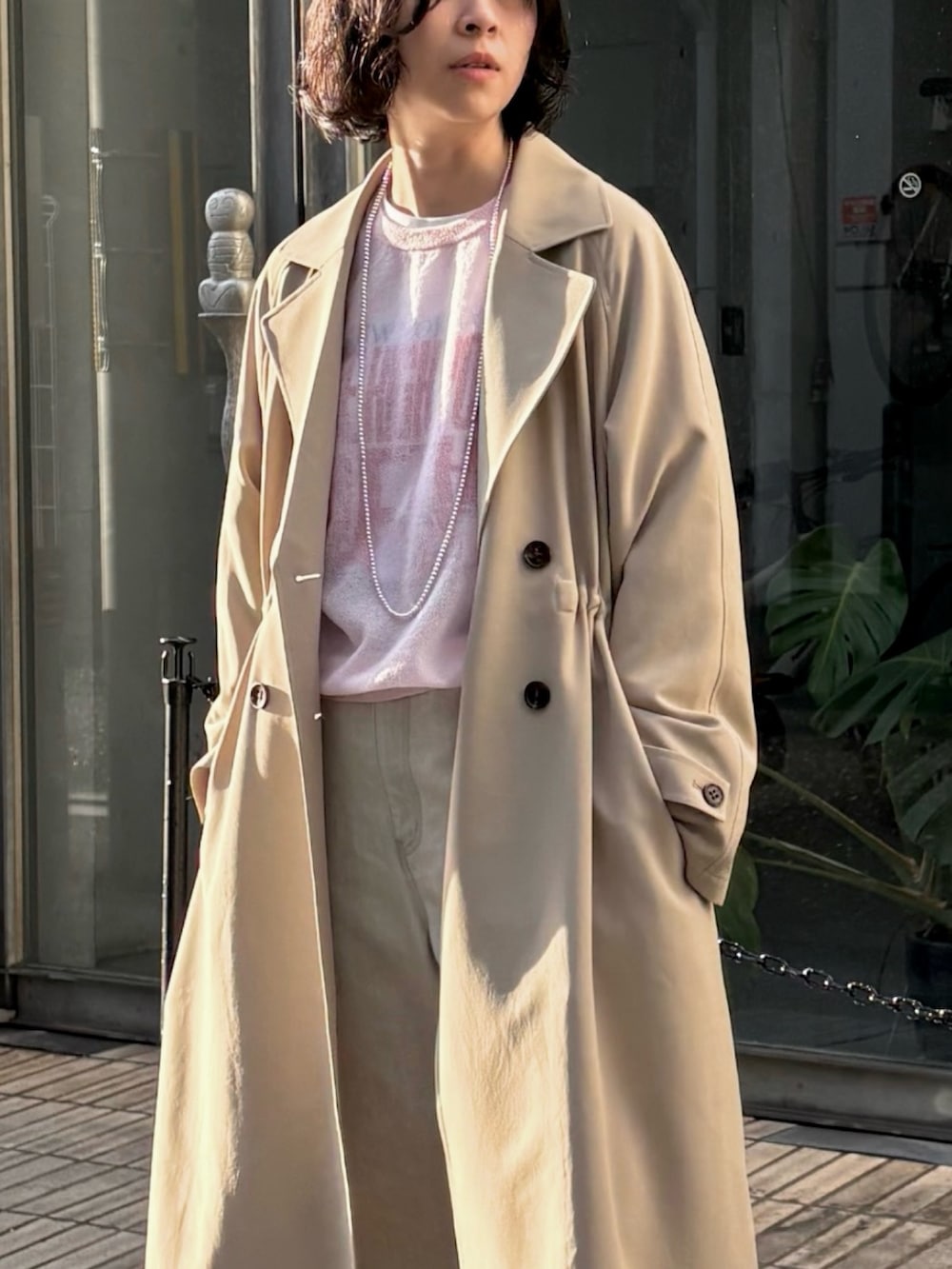 グレー系のデニムパンツ、ベージュ系のトレンチコート、ピンク系のニット/セーターを着用したレディースの冬コーディネートの2枚目の写真