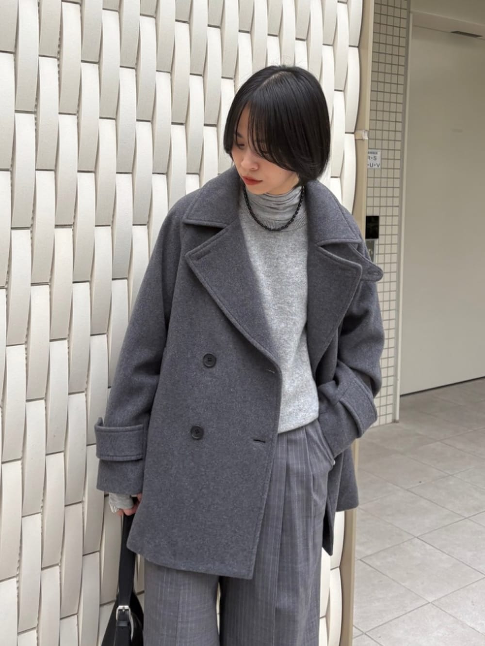 グレー系のピーコート、グリーン系のニット/セーター、グレー系のその他パンツを着用したレディースの秋コーディネートの5枚目の写真