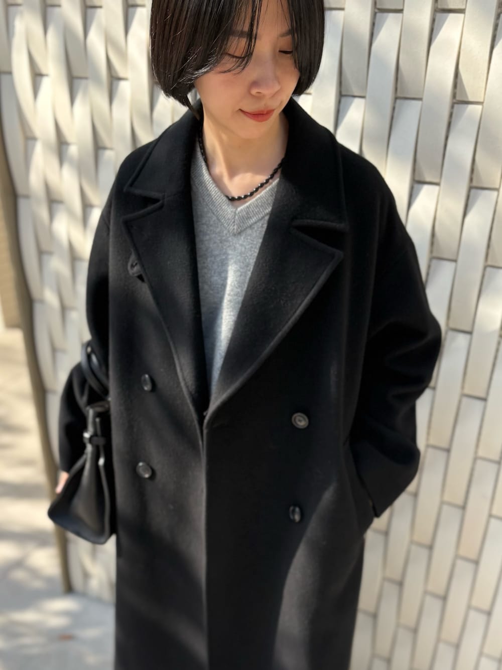 ブラック系のトートバッグ、ブラック系のチェスターコート、グリーン系のニット/セーターを着用したレディースの冬コーディネートの4枚目の写真