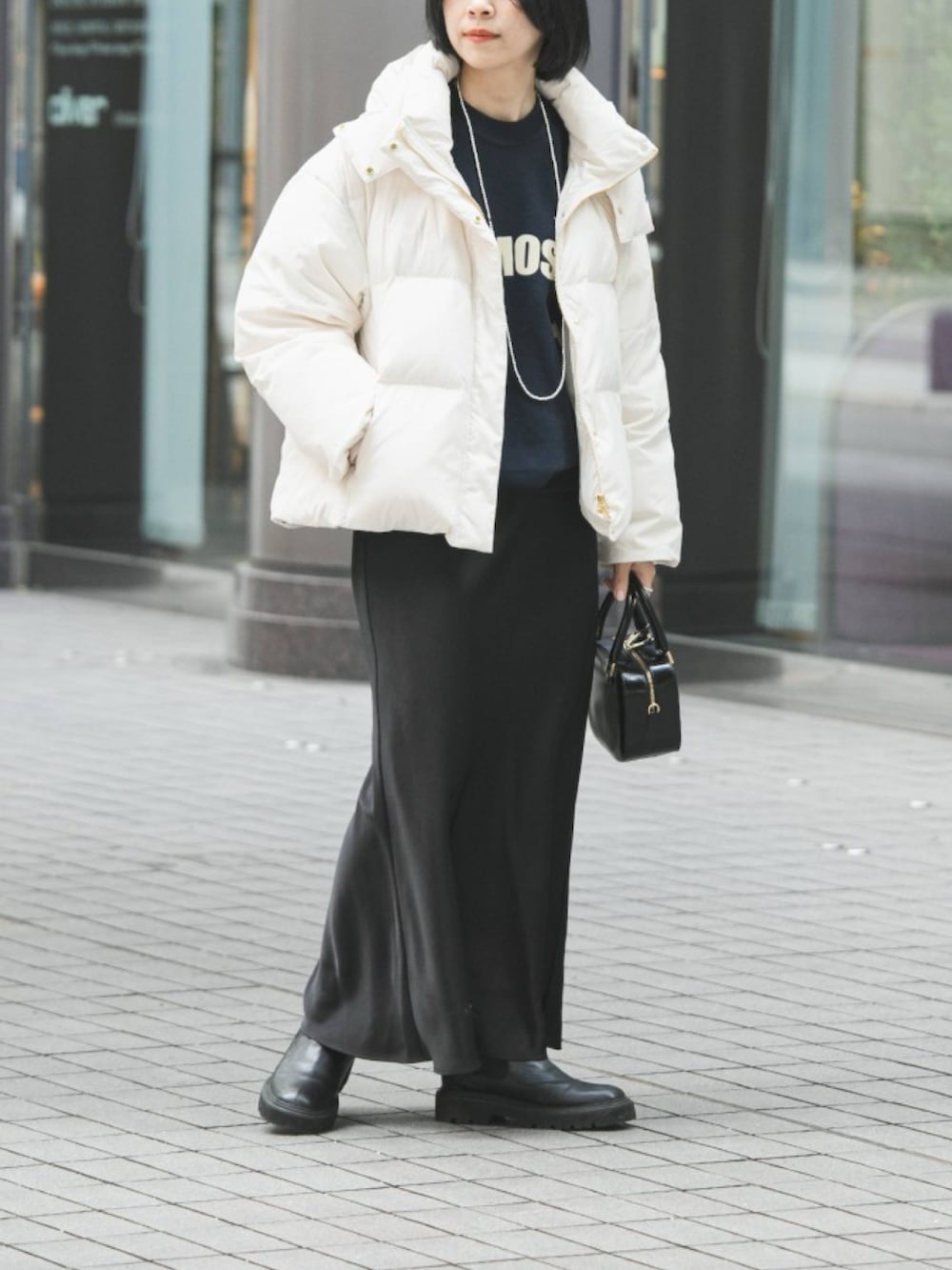 ブルー系のスウェット、ホワイト系のダウンジャケット/コート、ブラック系のスカートを着用したレディースの冬コーディネートの2枚目の写真