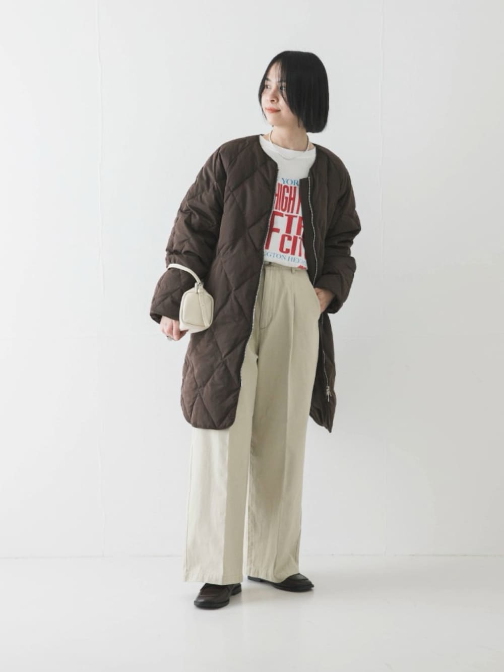 ブラウン系のダウンジャケット/コート、ホワイト系のTシャツ/カットソー、ブラウン系のローファーを着用したレディースの冬コーディネートの2枚目の写真