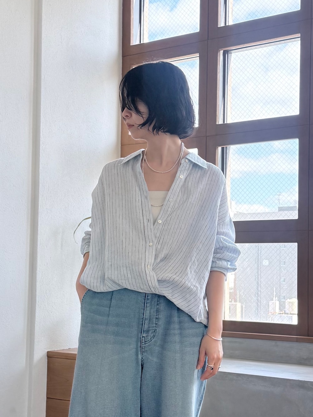 ブルー系のデニムパンツ、ブラック系のパンプス、ブルー系のシャツ/ブラウスを着用したレディースの春コーディネートの3枚目の写真