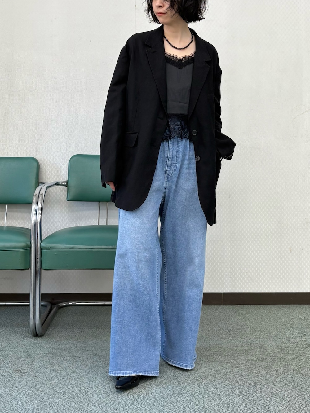 ブラック系のパンプス、ブルー系のデニムパンツ、ブラック系のキャミソールを着用したレディースの冬コーディネートの2枚目の写真