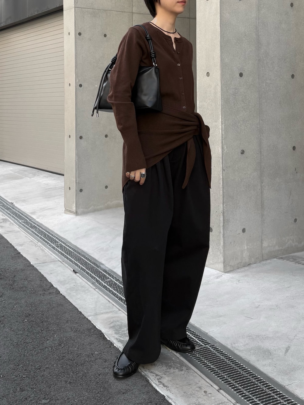 ブラック系のハンドバッグ、ブラウン系のカーディガン/ボレロ、ブラック系のその他パンツを着用したレディースの秋コーディネートの2枚目の写真
