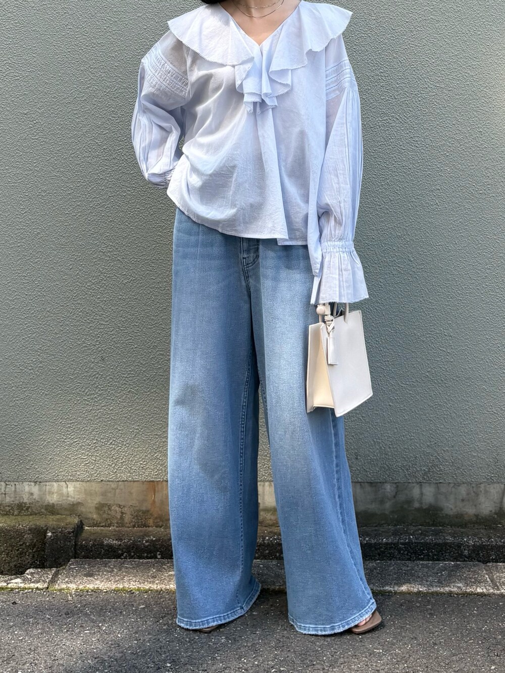 ブルー系のシャツ/ブラウス、ブルー系のデニムパンツ、ホワイト系のハンドバッグを着用したレディースの春コーディネートの2枚目の写真