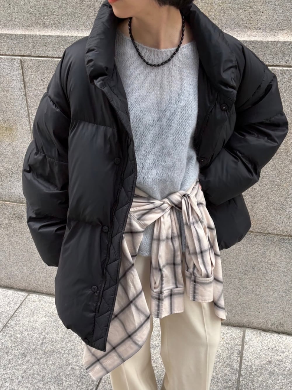 ベージュ系のブーツ、ブルー系のニット/セーター、ブラック系のダウンジャケット/コートを着用したレディースの秋コーディネートの4枚目の写真