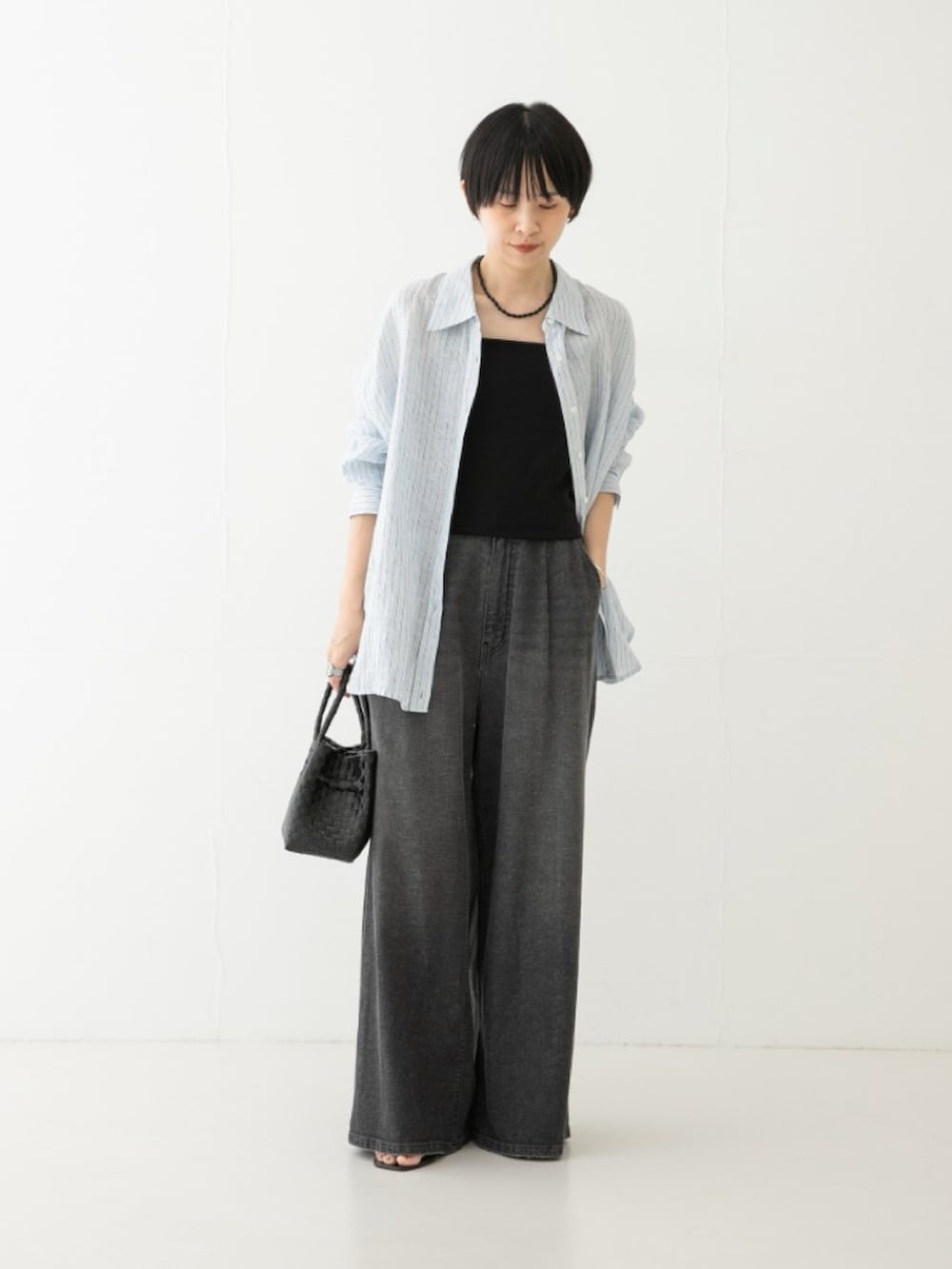 ブラック系のデニムパンツ、ブラック系のトートバッグ、ブルー系のシャツ/ブラウスを着用したレディースの夏コーディネートの2枚目の写真