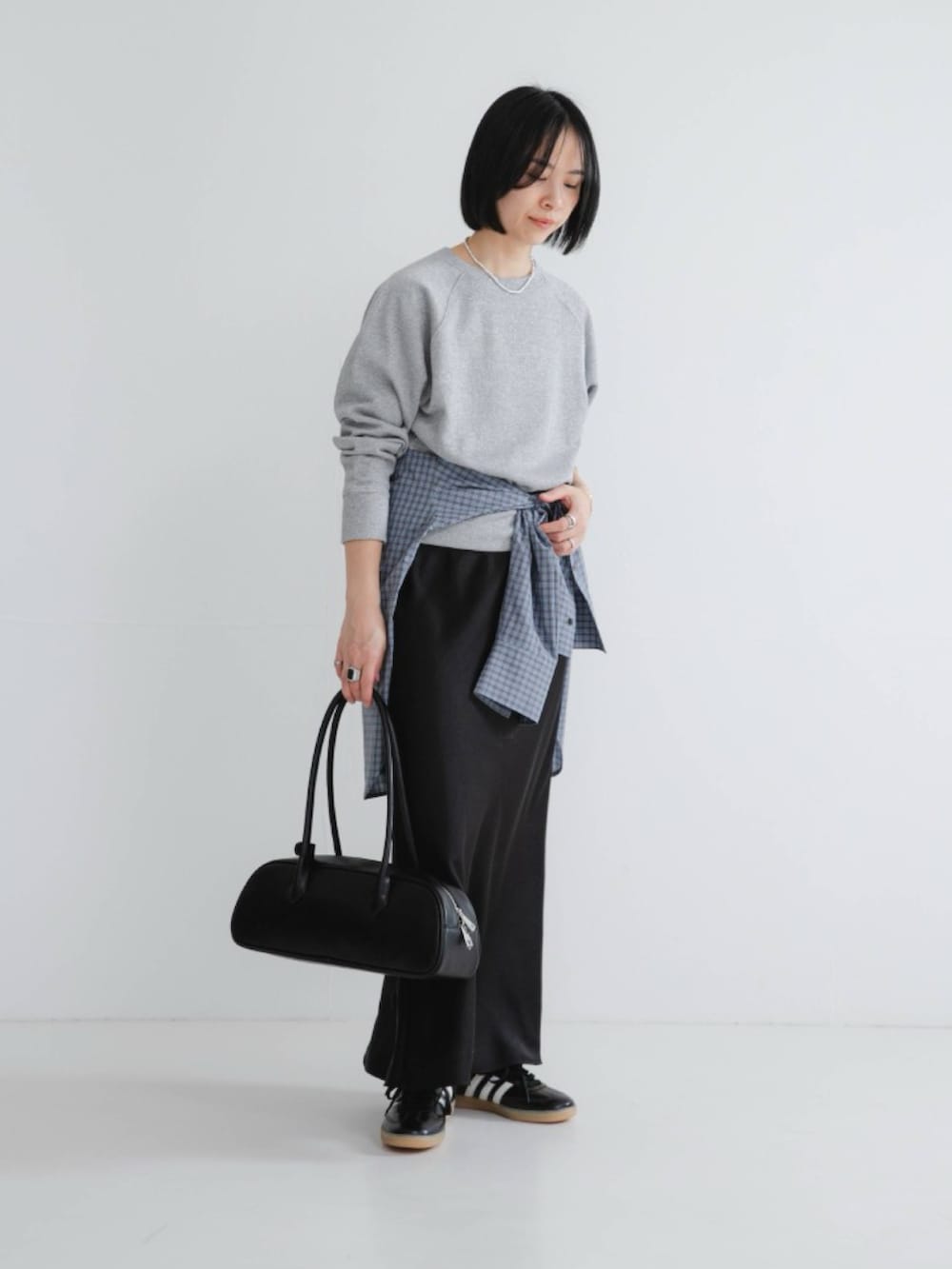 グレー系のスウェット、ブラック系のスカート、ブラック系のスニーカーを着用したレディースの冬コーディネートの2枚目の写真