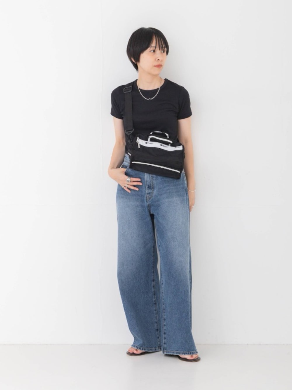 ブラック系のTシャツ/カットソー、ブラック系のショルダーバッグ、ブルー系のデニムパンツを着用したレディースの夏コーディネートの2枚目の写真