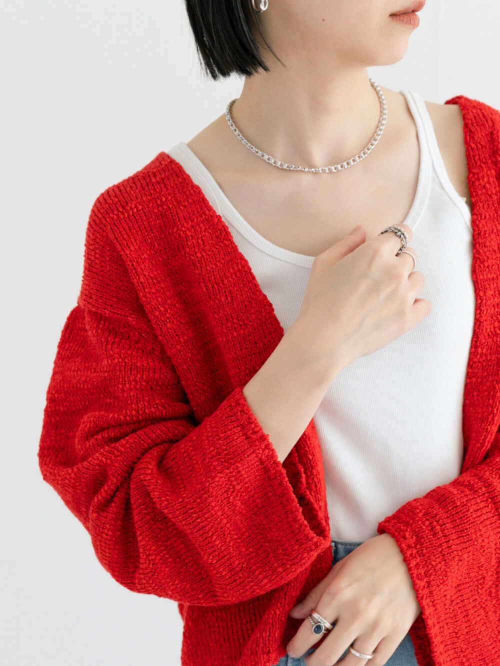 レッド系のカーディガン/ボレロ、ブルー系のデニムパンツ、シルバー系のブレスレットを着用したレディースの春コーディネートの2枚目の写真