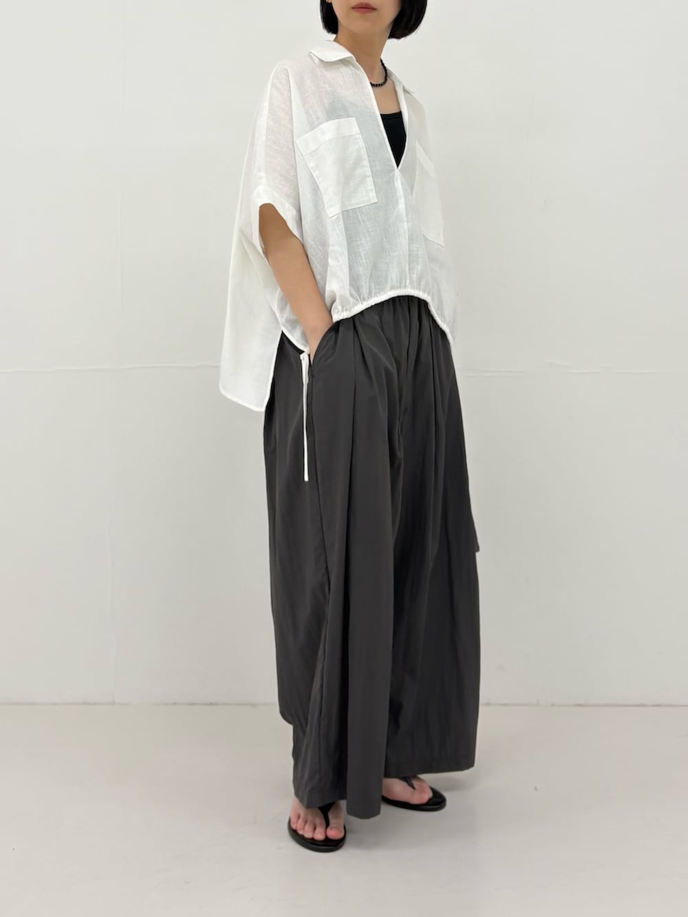 グレー系のその他パンツ、ホワイト系のシャツ/ブラウス、ブラック系のサンダルを着用したレディースの春コーディネートの2枚目の写真
