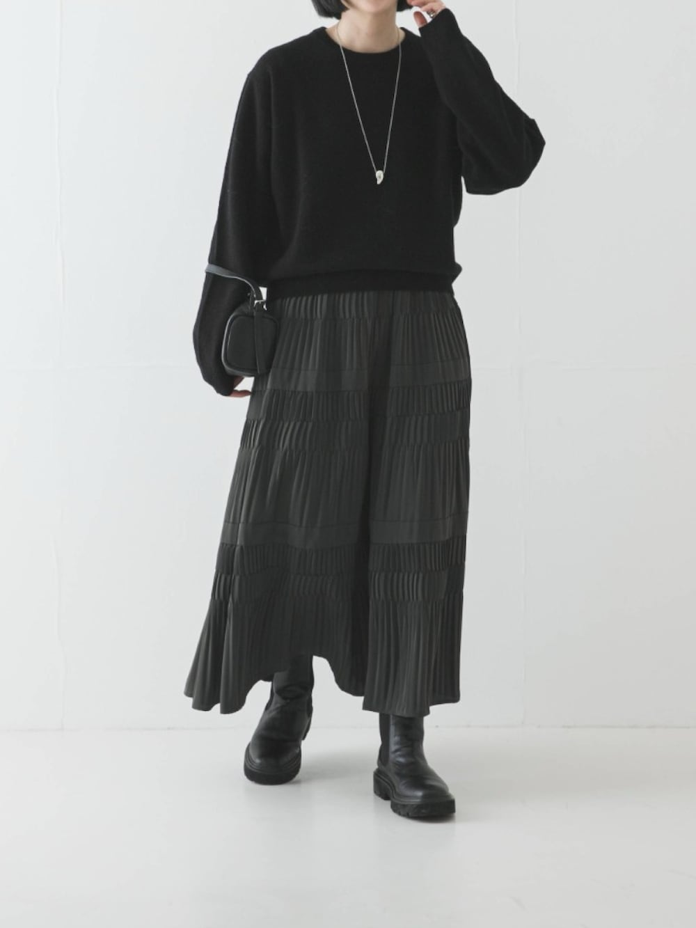 グリーン系のスカート、ブラック系のブーツ、ブラック系のニット/セーターを着用したレディースの冬コーディネートの2枚目の写真