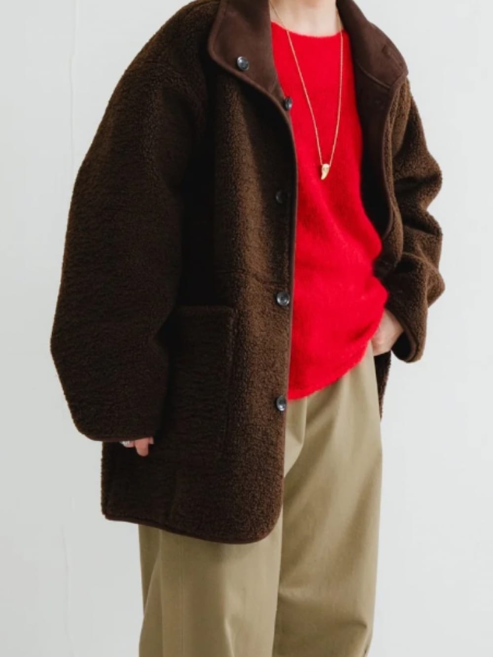 ブラウン系のムートンコート、ブラウン系のニット/セーター、ベージュ系のその他パンツを着用したレディースの冬コーディネートの3枚目の写真