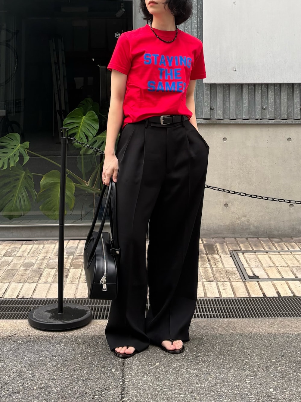 ブラック系のその他パンツ、ブラック系のショルダーバッグ、レッド系のTシャツ/カットソーを着用したレディースの冬コーディネートの2枚目の写真