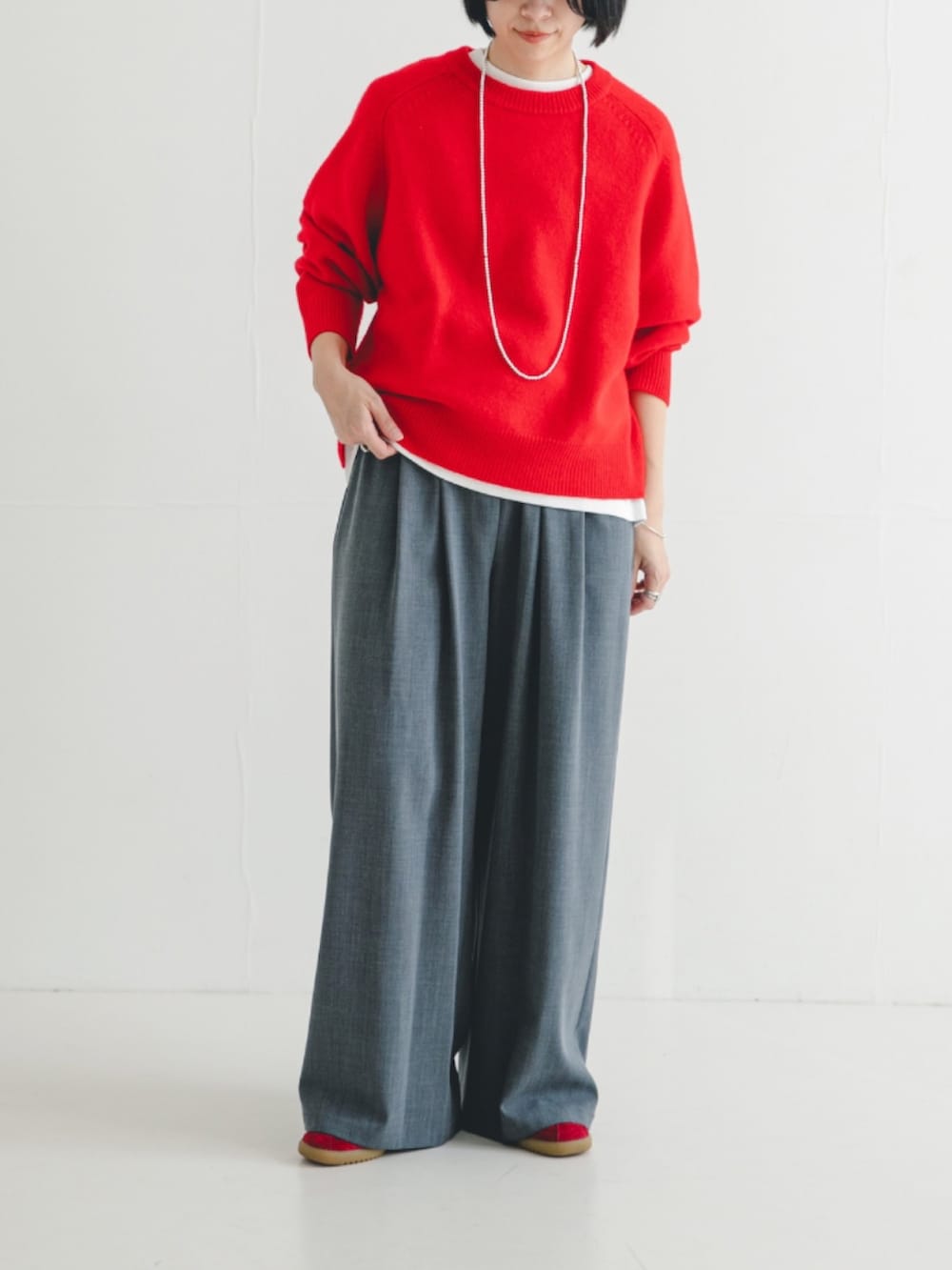 レッド系のニット/セーター、グレー系のその他パンツを着用したレディースの冬コーディネートの3枚目の写真