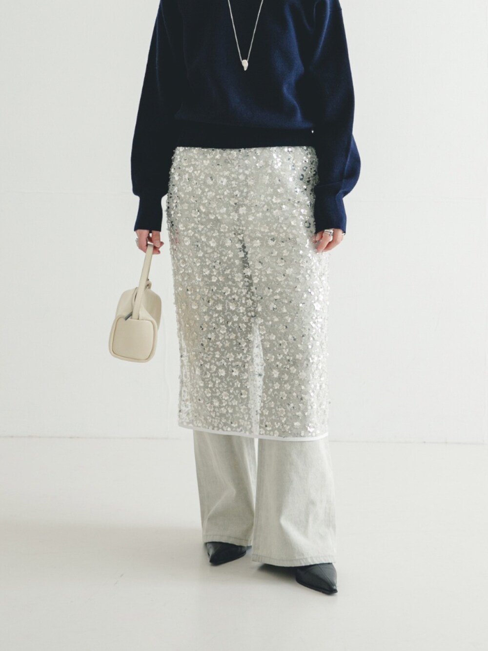 グレー系のデニムパンツ、ホワイト系のスカート、ブラック系のブーツを着用したレディースの冬コーディネートの3枚目の写真