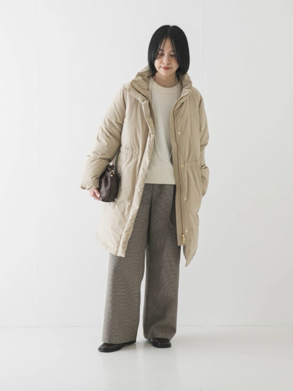 ベージュ系のダウンジャケット/コート、ホワイト系のニット/セーター、グリーン系のその他パンツを着用したレディースの冬コーディネートの2枚目の写真