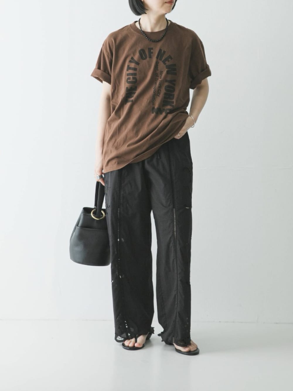 ブラウン系のTシャツ/カットソー、ブラック系のその他パンツ、ブラック系のハンドバッグを着用したレディースの春コーディネートの2枚目の写真