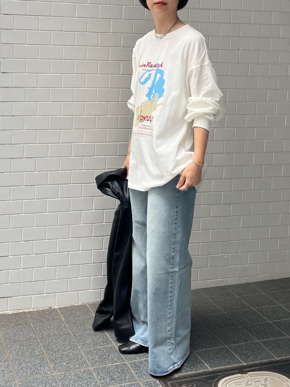 ブルー系のデニムパンツ、ブラック系のその他アウター、ホワイト系のTシャツ/カットソーを着用したレディースの秋コーディネートの2枚目の写真