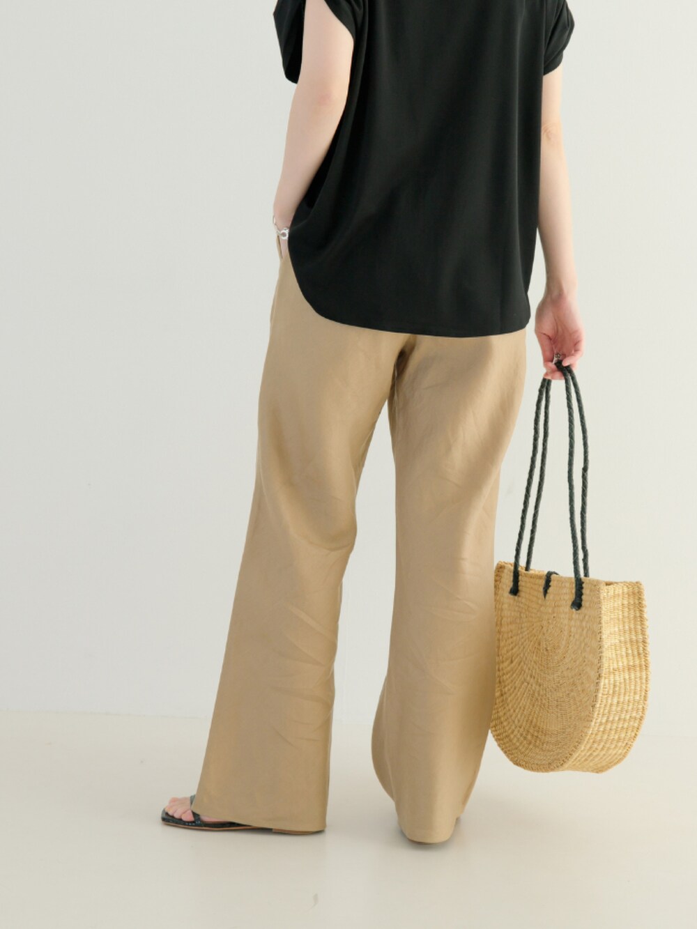 ブラック系のTシャツ/カットソー、ベージュ系のその他パンツ、ブラック系のハンドバッグを着用したレディースの春コーディネートの5枚目の写真