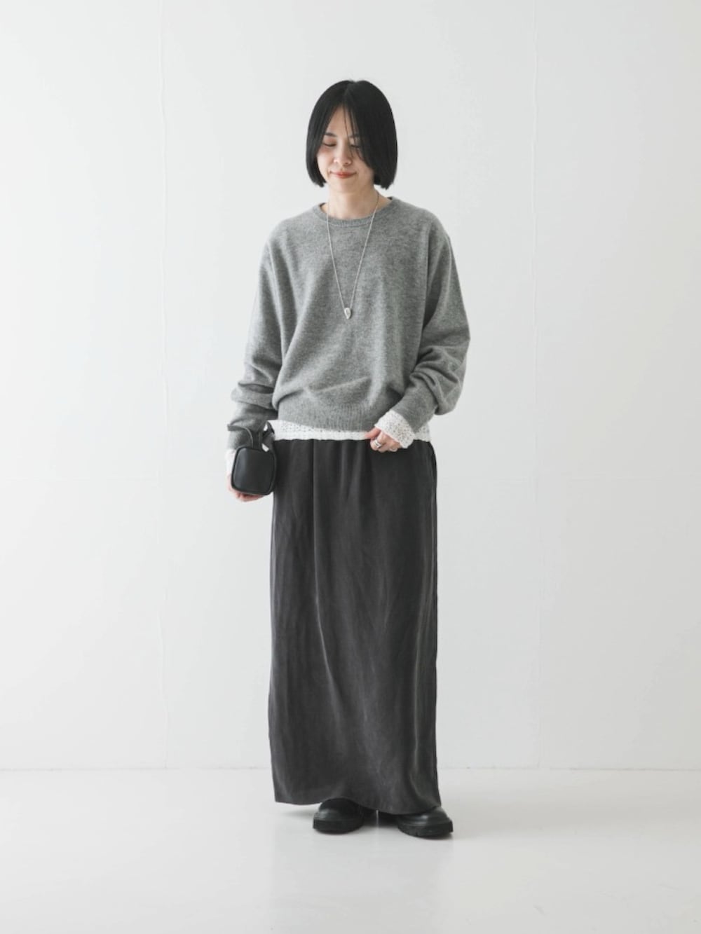 ホワイト系のTシャツ/カットソー、グレー系のスカート、ブラック系のブーツを着用したレディースの冬コーディネートの2枚目の写真