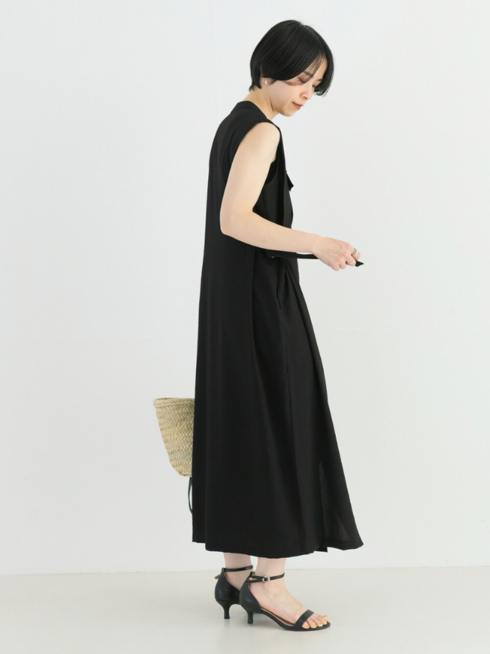 ブラック系のワンピース、ブラック系のかごバッグ、ブラック系のサンダルを着用したレディースの春コーディネートの2枚目の写真