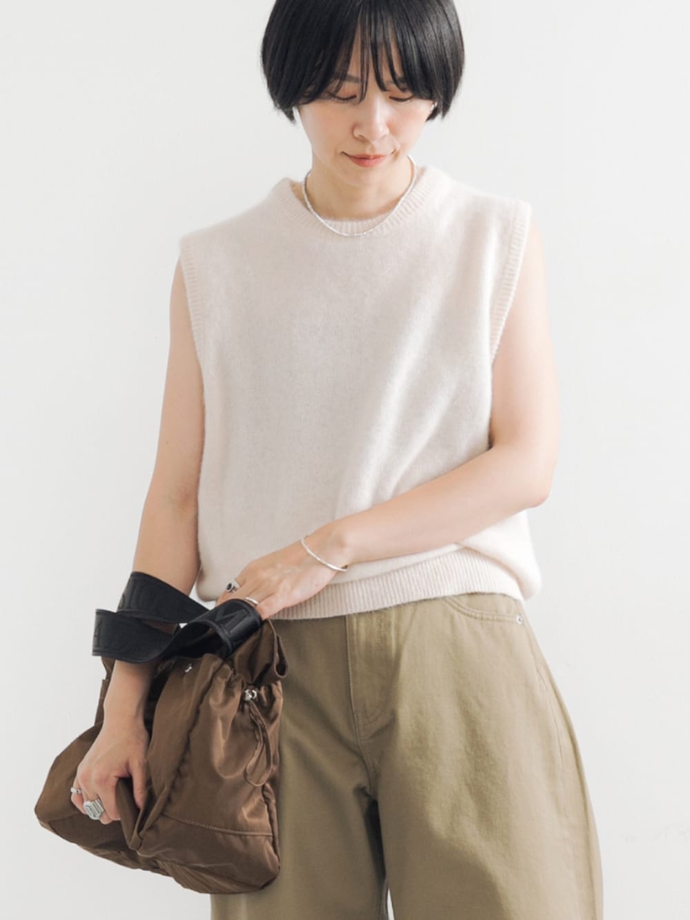 ホワイト系のベスト、ブラウン系のショルダーバッグ、ベージュ系のその他パンツを着用したレディースの夏コーディネートの2枚目の写真