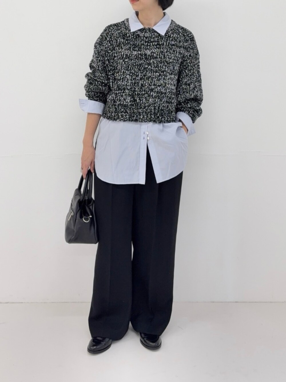 ブラック系のニット/セーター、ブルー系のシャツ/ブラウス、ブラック系のハンドバッグを着用したレディースの冬コーディネートの2枚目の写真