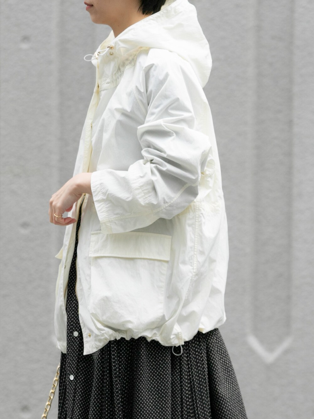 ホワイト系のマウンテンパーカー、ブラック系のショルダーバッグ、ブラック系のワンピースを着用したレディースの春コーディネートの4枚目の写真