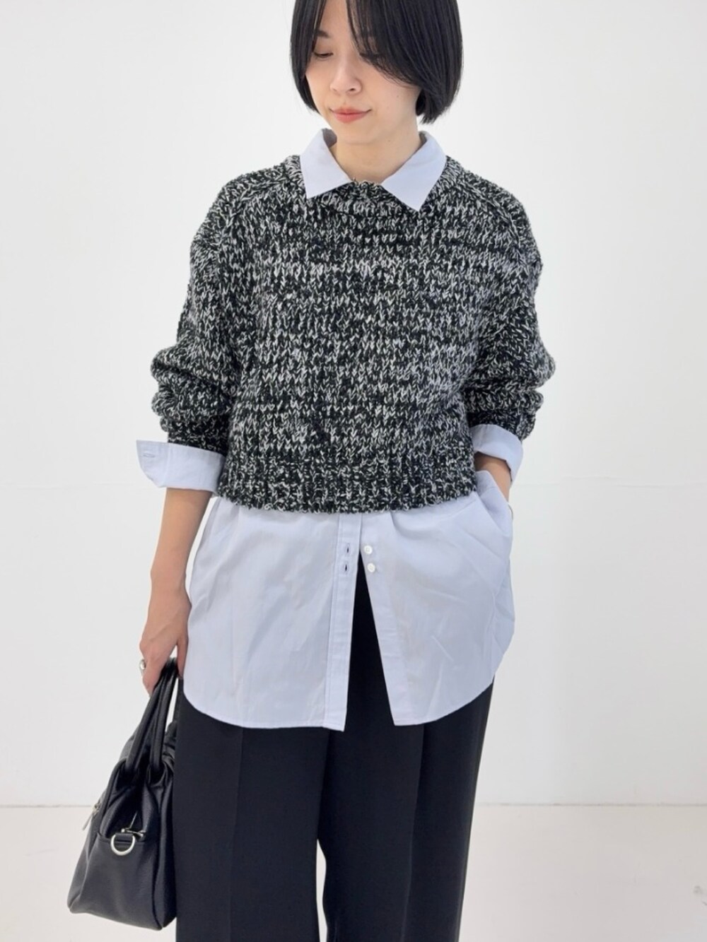 ブラック系のニット/セーター、ブルー系のシャツ/ブラウス、ブラック系のハンドバッグを着用したレディースの冬コーディネートの4枚目の写真